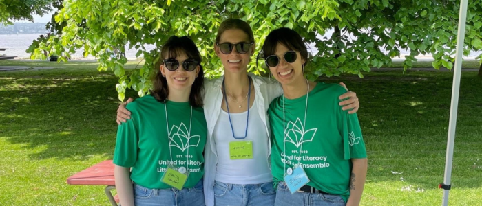 Three people wearing United for Literacy t-shirts standing at a table outside