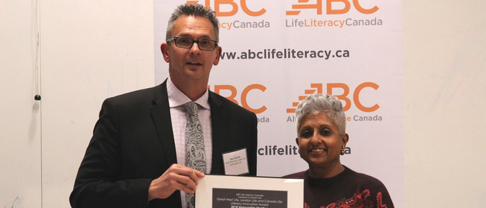 A woman with brown eyes and silver hair and a taller man with glasses are holding a certificate 