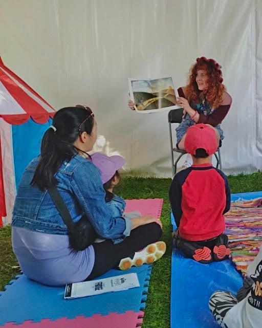 A Community Coordinator reading a book during a Reading Tent